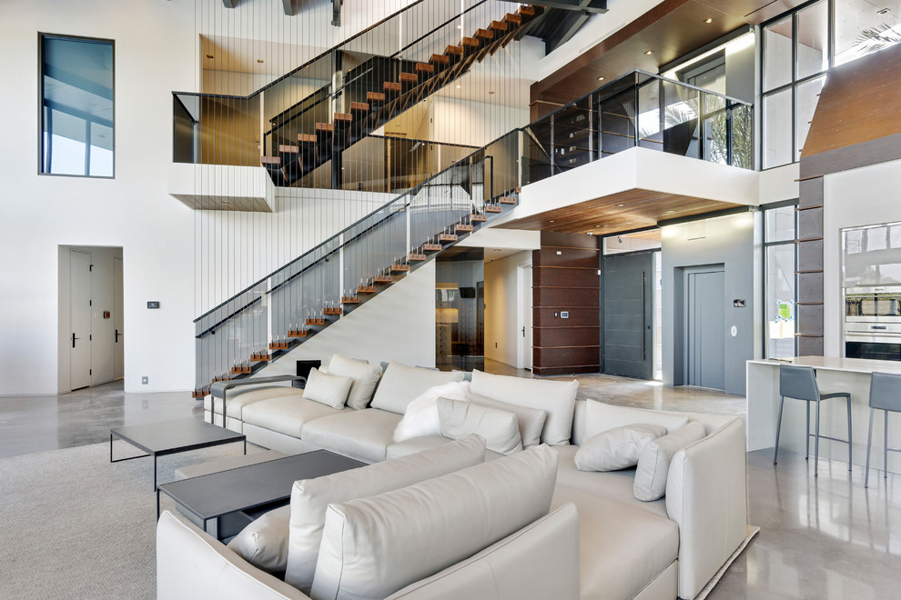 Modelo de salón abierto moderno grande con paredes blancas, suelo de cemento y suelo gris
