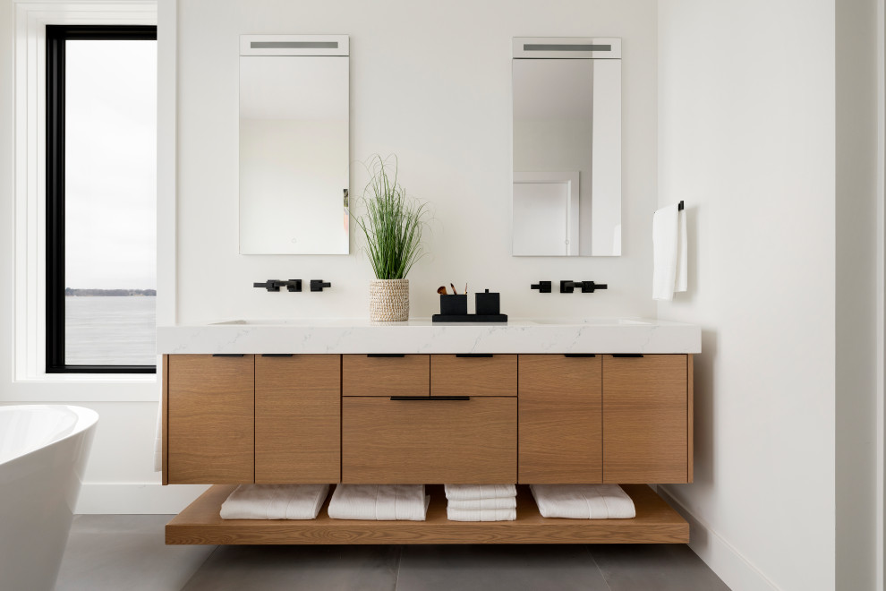 Design ideas for a mid-sized contemporary master bathroom in Minneapolis with flat-panel cabinets, beige cabinets, a freestanding tub, a curbless shower, a one-piece toilet, white walls, cement tiles, an undermount sink, marble benchtops, grey floor, an open shower, white benchtops, an enclosed toilet, a double vanity and a floating vanity.