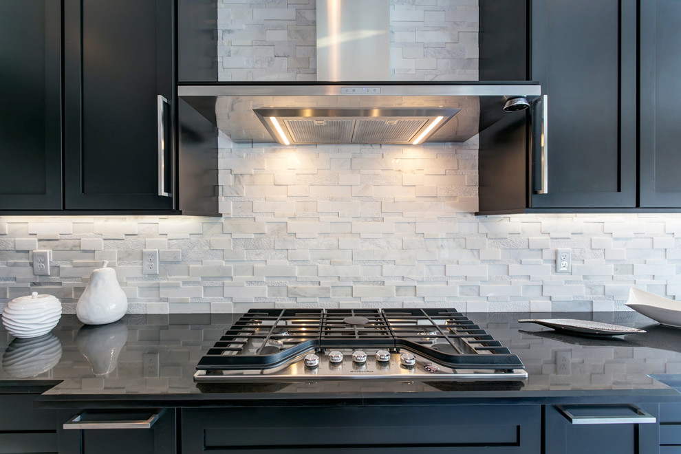 Large trendy l-shaped white floor open concept kitchen photo in Seattle with an undermount sink, shaker cabinets, black cabinets, granite countertops, white backsplash, stone tile backsplash, stainless steel appliances and an island