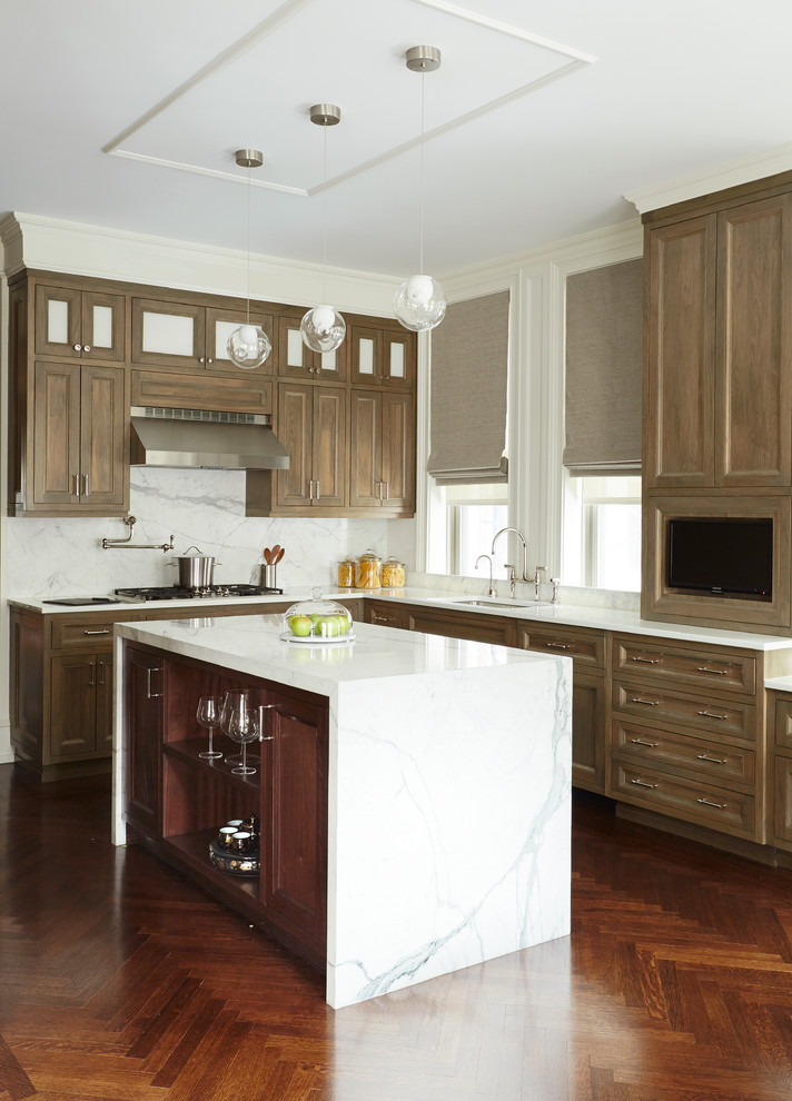This is an example of a large transitional l-shaped eat-in kitchen in New York with an undermount sink, recessed-panel cabinets, light wood cabinets, white splashback, dark hardwood floors, with island, marble benchtops, stone slab splashback and stainless steel appliances.