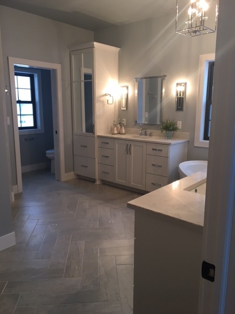 This is an example of a mid-sized transitional master bathroom in Milwaukee with white cabinets, grey floor, shaker cabinets, a freestanding tub, porcelain floors, an undermount sink and quartzite benchtops.