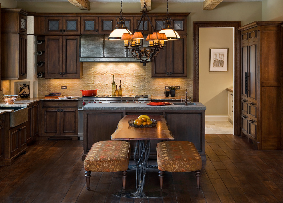 Photo of a traditional u-shaped kitchen in Chicago with a farmhouse sink, recessed-panel cabinets, dark wood cabinets, beige splashback, stone tile splashback, stainless steel appliances, dark hardwood floors and with island.
