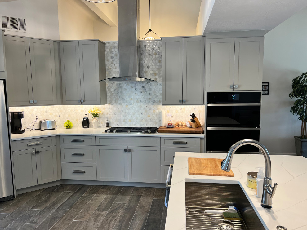 Example of a large transitional u-shaped porcelain tile and brown floor eat-in kitchen design in Austin with an undermount sink, shaker cabinets, gray cabinets, quartz countertops, white backsplash, marble backsplash, stainless steel appliances, an island and white countertops