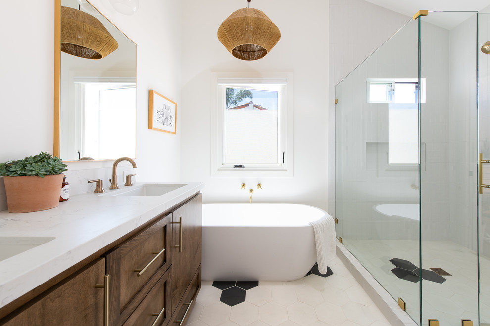 Transitional white floor freestanding bathtub photo in Orange County with recessed-panel cabinets, dark wood cabinets, white walls, an undermount sink, a hinged shower door and white countertops