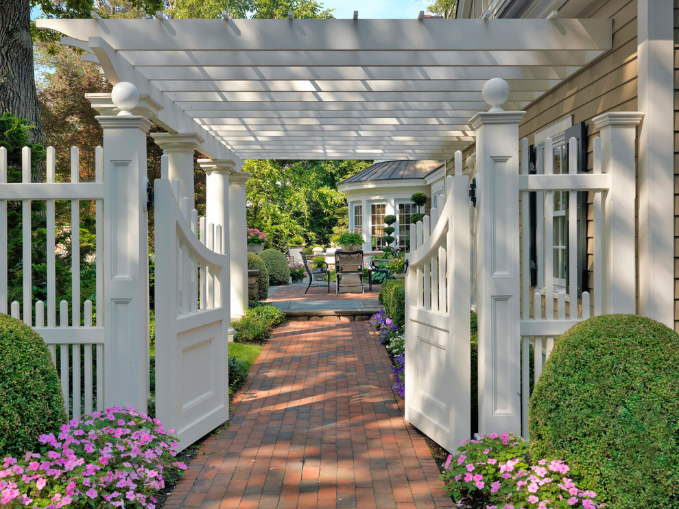 This is an example of a large classic back partial sun pergola in Boston with brick paving and a garden path.