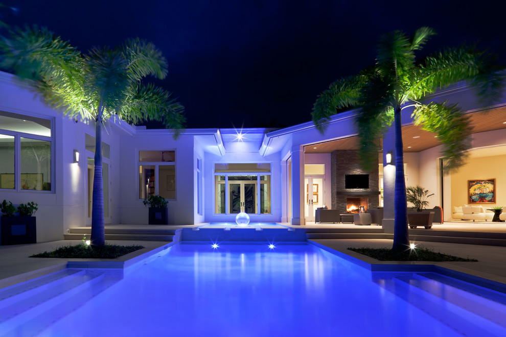 Contemporary backyard rectangular pool in Miami with natural stone pavers.
