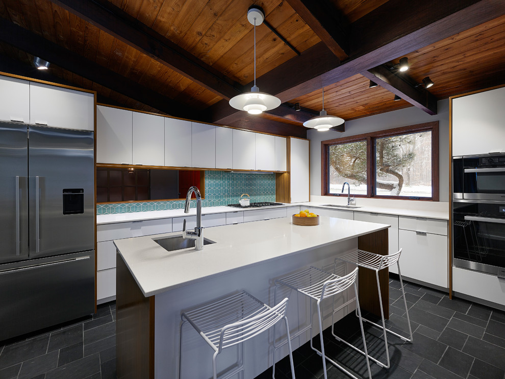 This is an example of a mid-sized midcentury l-shaped separate kitchen in Baltimore with an undermount sink, flat-panel cabinets, white cabinets, quartz benchtops, green splashback, ceramic splashback, stainless steel appliances, slate floors, with island and grey floor.