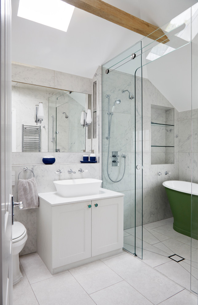 Mid-sized transitional master wet room bathroom in London with shaker cabinets, a freestanding tub, a one-piece toilet, gray tile, porcelain tile, porcelain floors, grey floor, a sliding shower screen, white benchtops, white cabinets and a vessel sink.