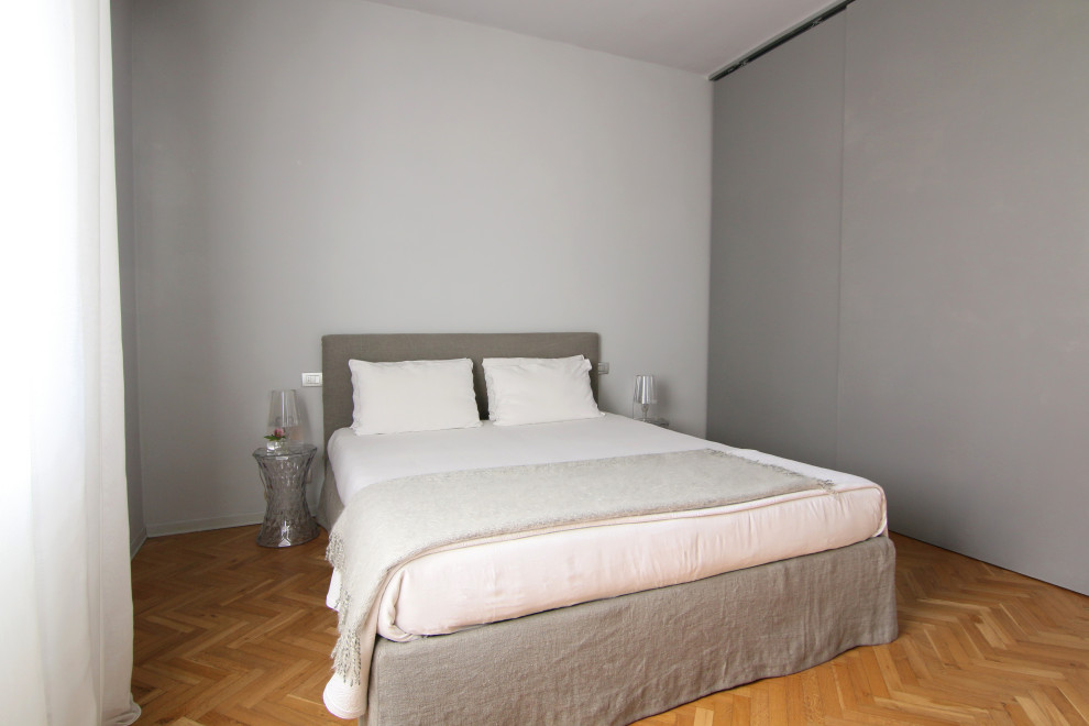 Foto di una camera matrimoniale minimal di medie dimensioni con pareti grigie e parquet chiaro