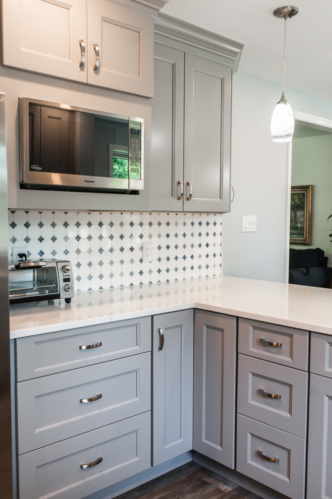 This is an example of a classic kitchen/diner in Wilmington with recessed-panel cabinets, grey cabinets, engineered stone countertops, white splashback, mosaic tiled splashback, vinyl flooring, a breakfast bar, grey floors and white worktops.