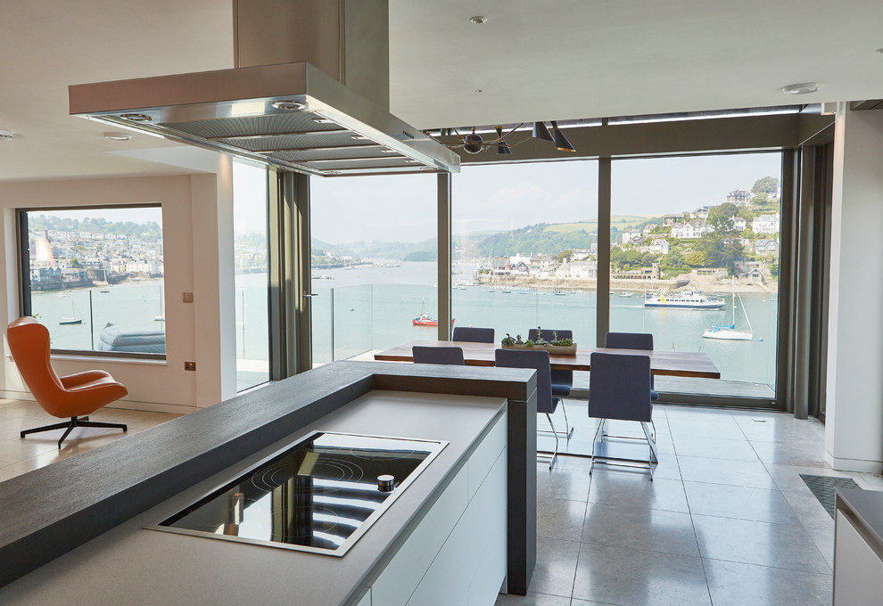 Small beach style galley open plan kitchen in Devon with flat-panel cabinets, white cabinets, solid surface benchtops, brown splashback, timber splashback, stainless steel appliances and porcelain floors.
