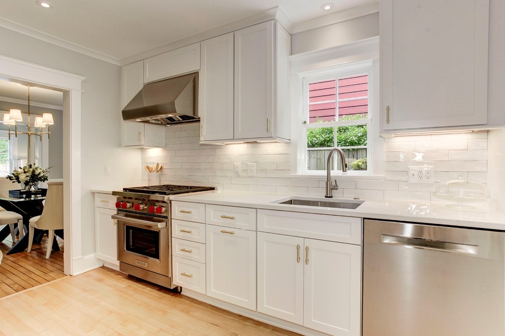Inspiration for a transitional light wood floor kitchen remodel in DC Metro with shaker cabinets, white cabinets, quartz countertops, white backsplash, ceramic backsplash, stainless steel appliances and white countertops