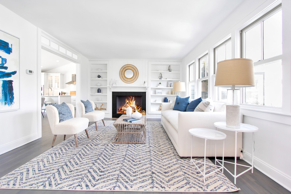 Mid-sized beach style formal enclosed living room in New York with white walls, medium hardwood floors, a standard fireplace, a brick fireplace surround, black floor and planked wall panelling.