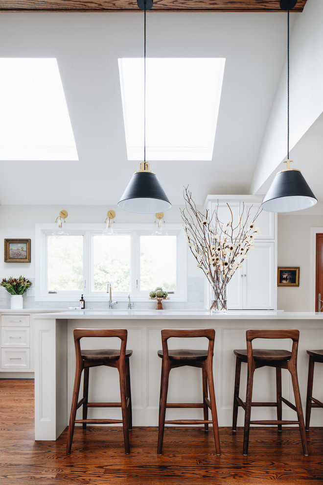 Kitchen - large transitional galley medium tone wood floor and brown floor kitchen idea in Chicago with an undermount sink, shaker cabinets, white cabinets, an island and white countertops