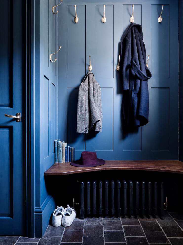 Mid-sized traditional mudroom in London with blue walls and black floor.