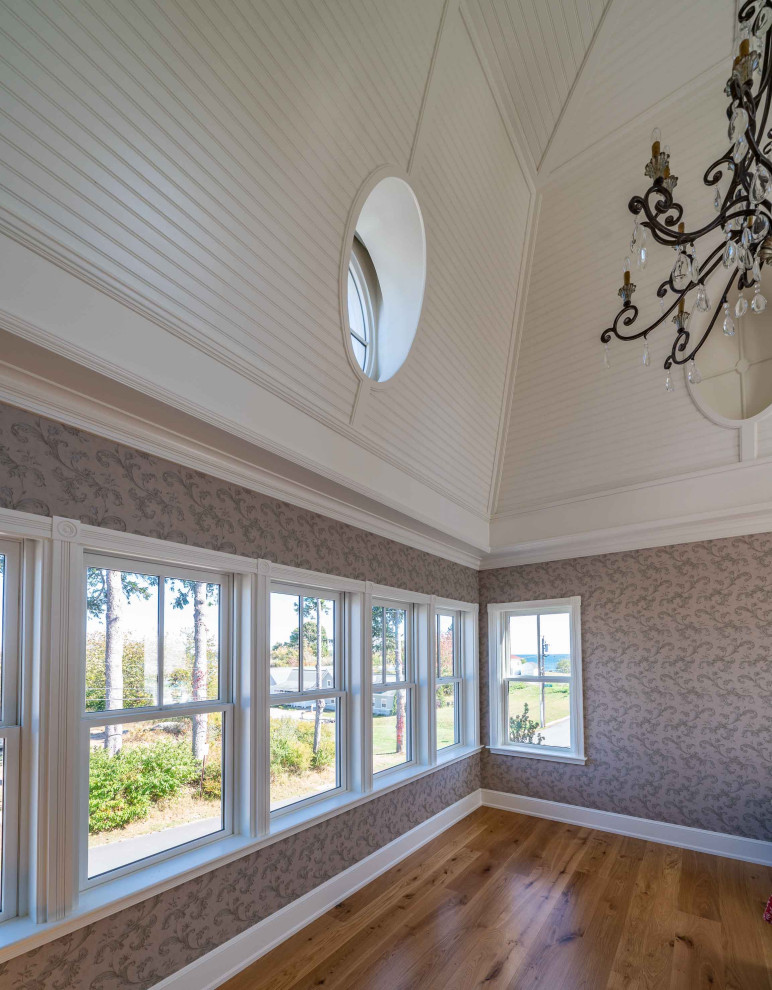 Victorian master bedroom in Boston with medium hardwood flooring, a vaulted ceiling and wallpapered walls.