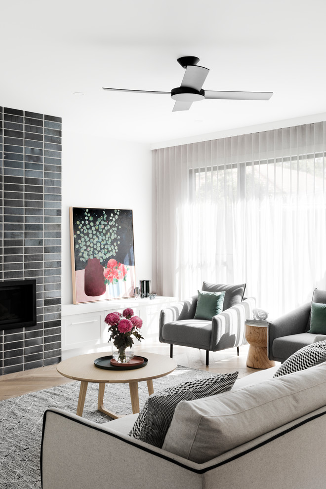 This is an example of a contemporary open concept family room in Melbourne with white walls, medium hardwood floors, a standard fireplace, a brick fireplace surround, a wall-mounted tv and brown floor.