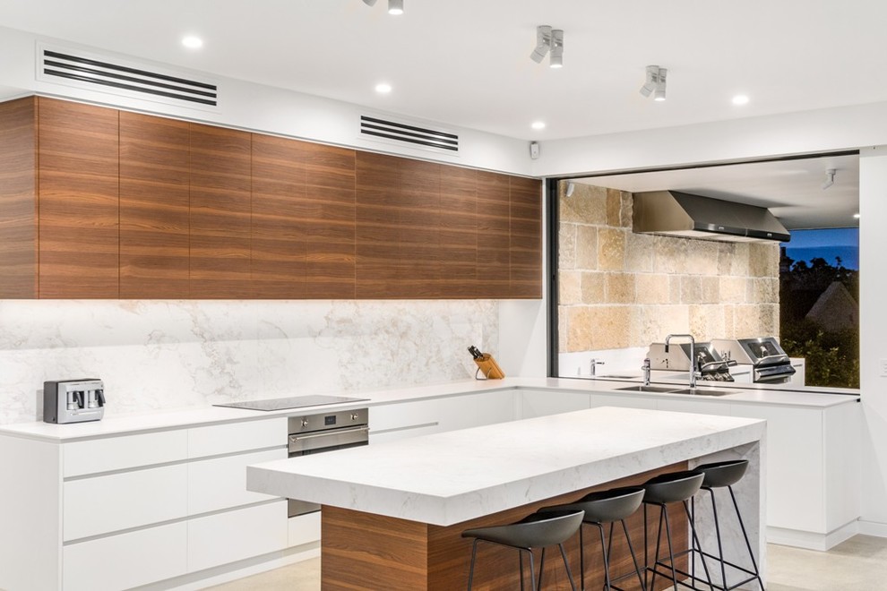 This is an example of a mid-sized contemporary galley eat-in kitchen in Sydney with a double-bowl sink, flat-panel cabinets, white cabinets, marble benchtops, white splashback, marble splashback, stainless steel appliances, concrete floors, with island and beige floor.