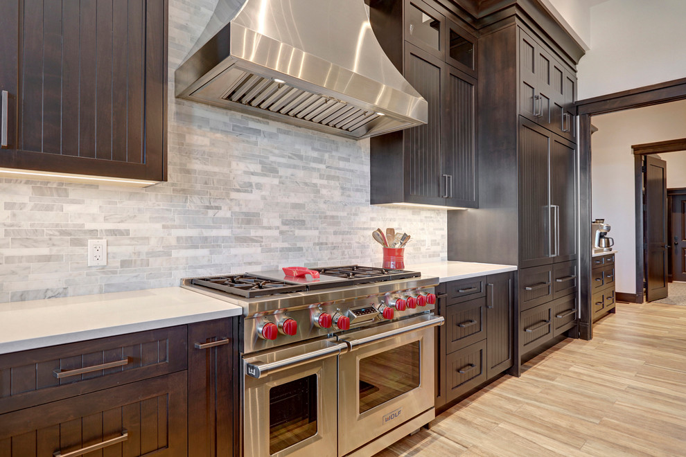 Example of a transitional porcelain tile kitchen design in Calgary with an undermount sink, shaker cabinets, dark wood cabinets, quartzite countertops, multicolored backsplash, stainless steel appliances and an island