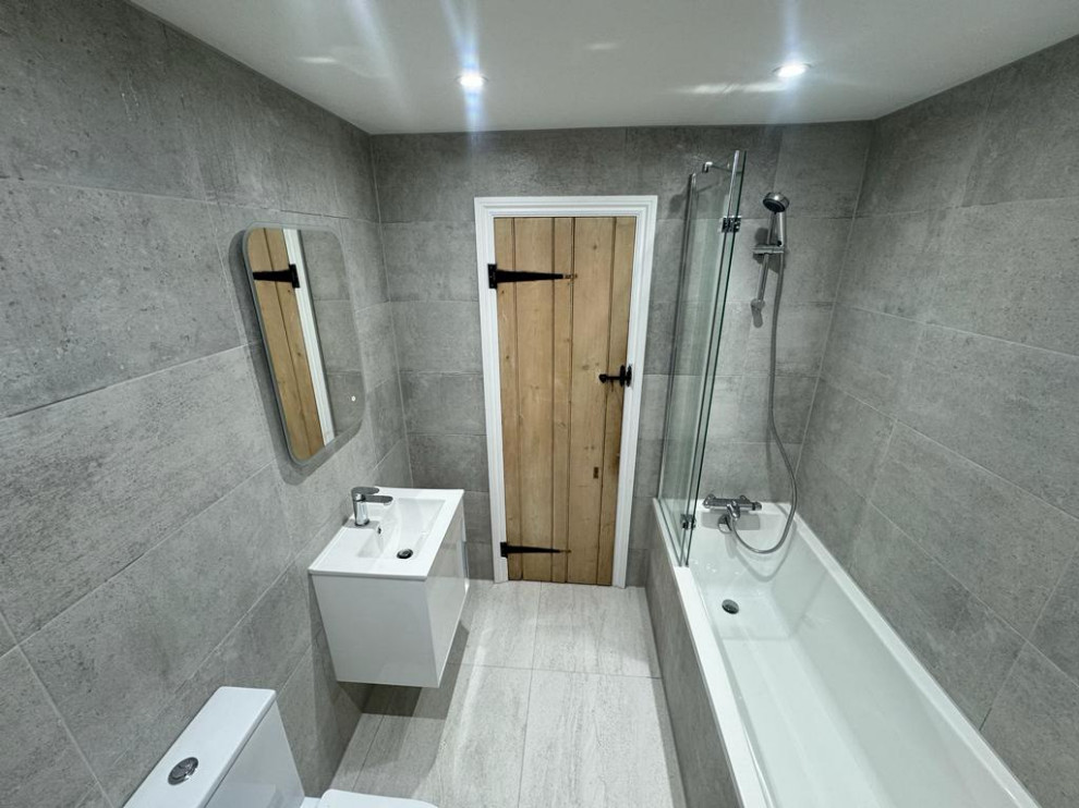 Стильный дизайн: маленькая серо-белая ванная комната в современном стиле с фасадами в стиле шейкер, белыми фасадами, ванной в нише, душем в нише, унитазом-моноблоком, серой плиткой, серыми стенами, полом из керамической плитки, подвесной раковиной, столешницей из гранита, серым полом, душем с раздвижными дверями, белой столешницей, тумбой под одну раковину, подвесной тумбой, кессонным потолком и керамической плиткой для на участке и в саду - последний тренд