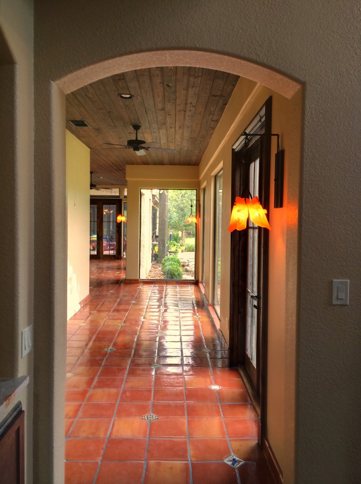 Design ideas for a mid-sized mediterranean hallway in Austin with beige walls, terra-cotta floors and red floor.