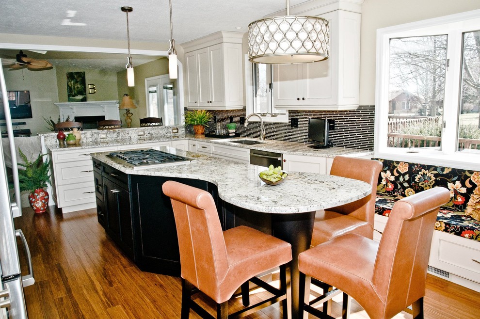 Inspiration for a mid-sized l-shaped medium tone wood floor open concept kitchen remodel with an integrated sink, recessed-panel cabinets, white cabinets, granite countertops, black backsplash, matchstick tile backsplash, stainless steel appliances and an island
