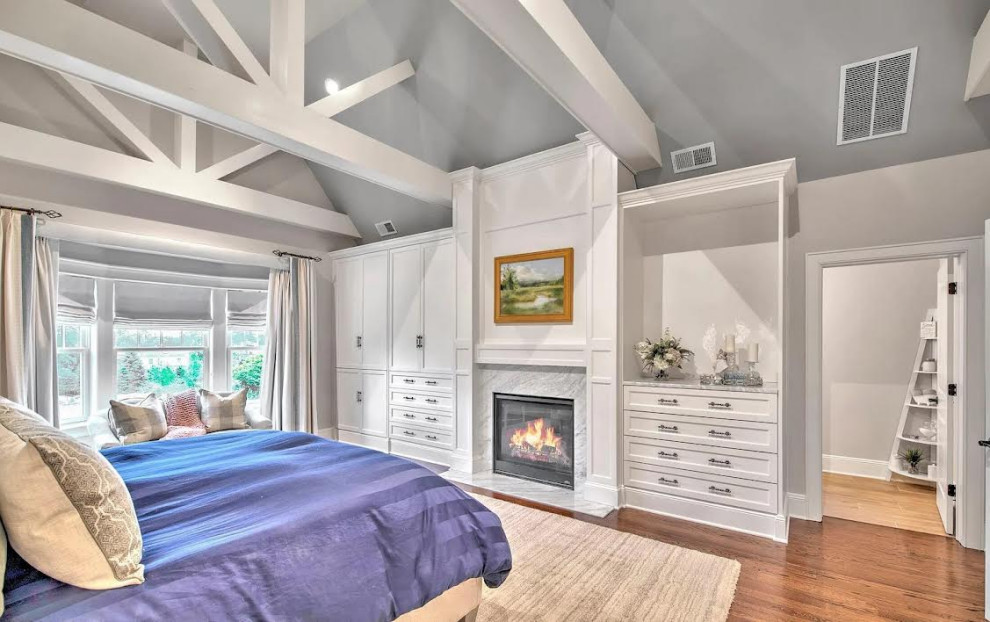 Photo of a large contemporary master bedroom in Bridgeport with medium hardwood floors, a ribbon fireplace, a wood fireplace surround, brown floor, decorative wall panelling and wood walls.