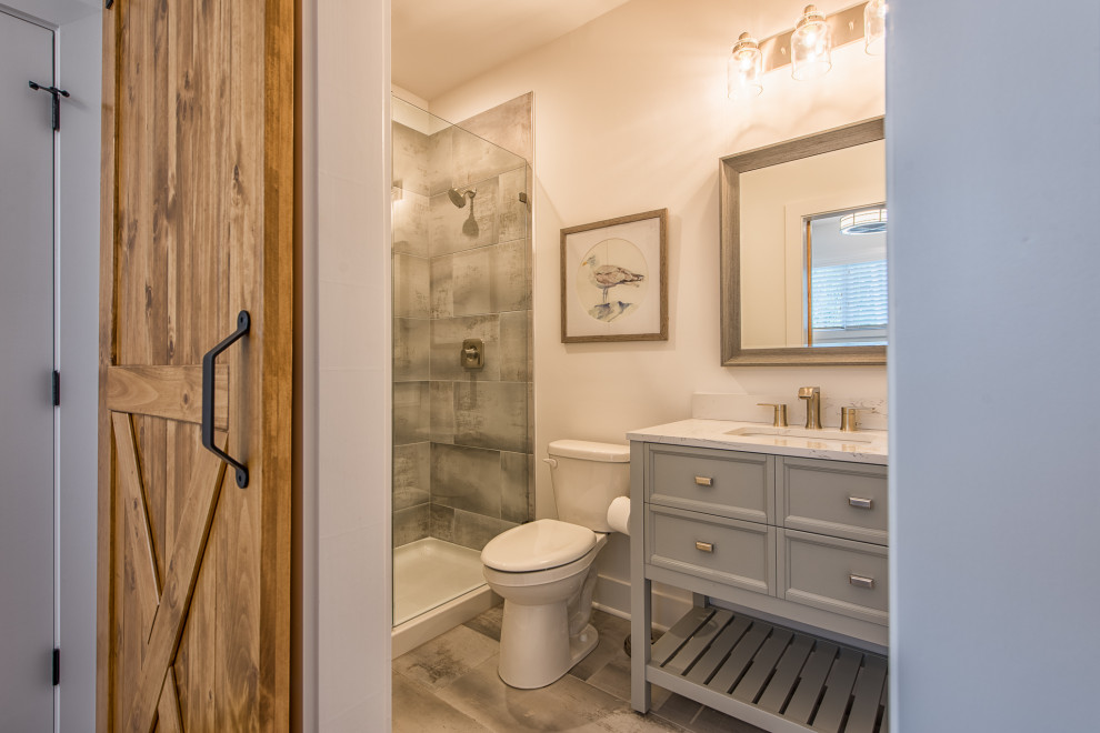 This is an example of a transitional bathroom in Charlotte with recessed-panel cabinets, grey cabinets, an alcove shower, gray tile, white walls, an undermount sink, grey floor, grey benchtops, a single vanity and a freestanding vanity.