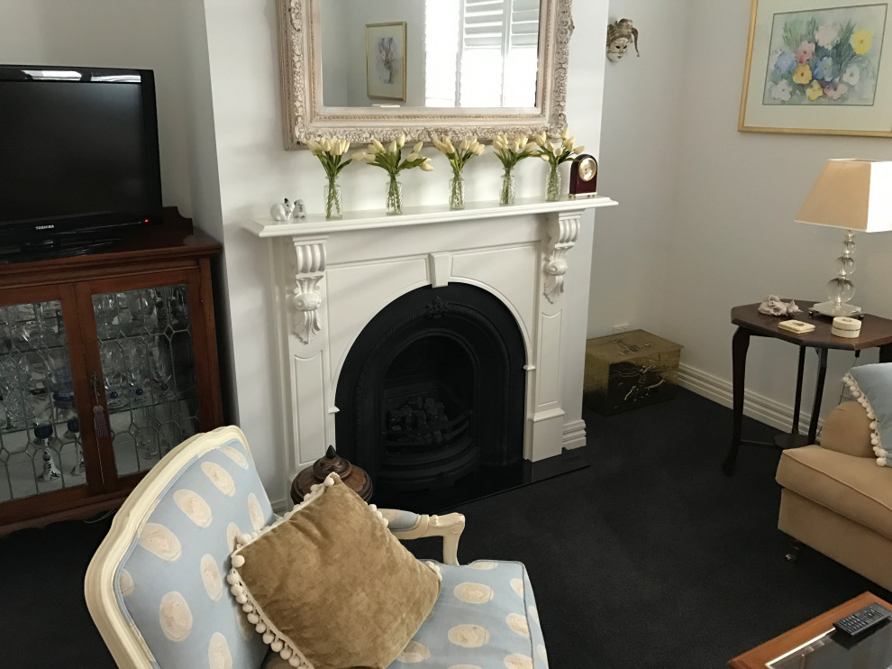Inspiration for a small traditional enclosed family room in Melbourne with white walls, carpet, a standard fireplace, a tile fireplace surround and black floor.