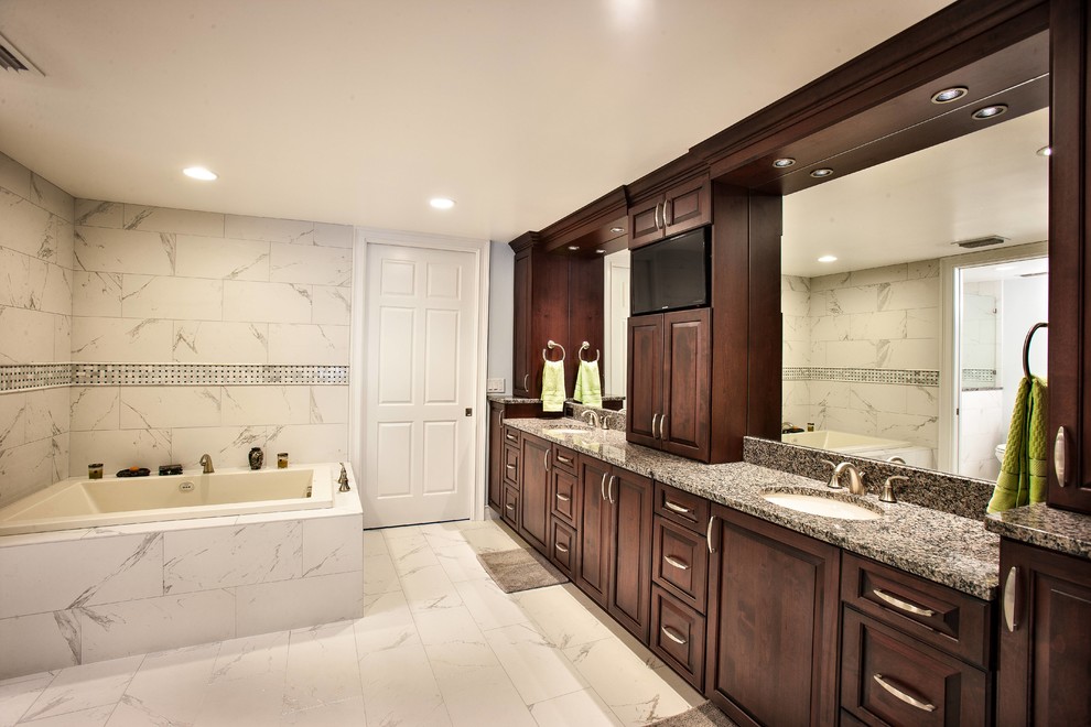 Large traditional master bathroom in Tampa with a drop-in tub, grey walls, marble floors, an undermount sink, raised-panel cabinets, dark wood cabinets, a corner shower, gray tile, white tile, stone tile and granite benchtops.