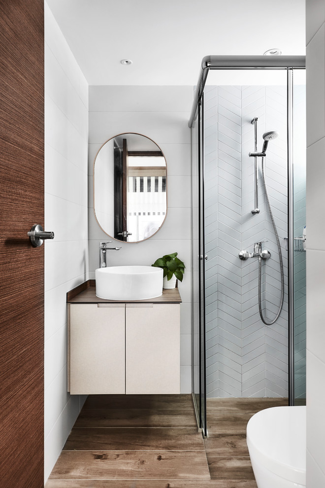 Contemporary 3/4 bathroom in Singapore with flat-panel cabinets, white cabinets, a curbless shower, white tile, white walls, a vessel sink, brown floor, a sliding shower screen and brown benchtops.