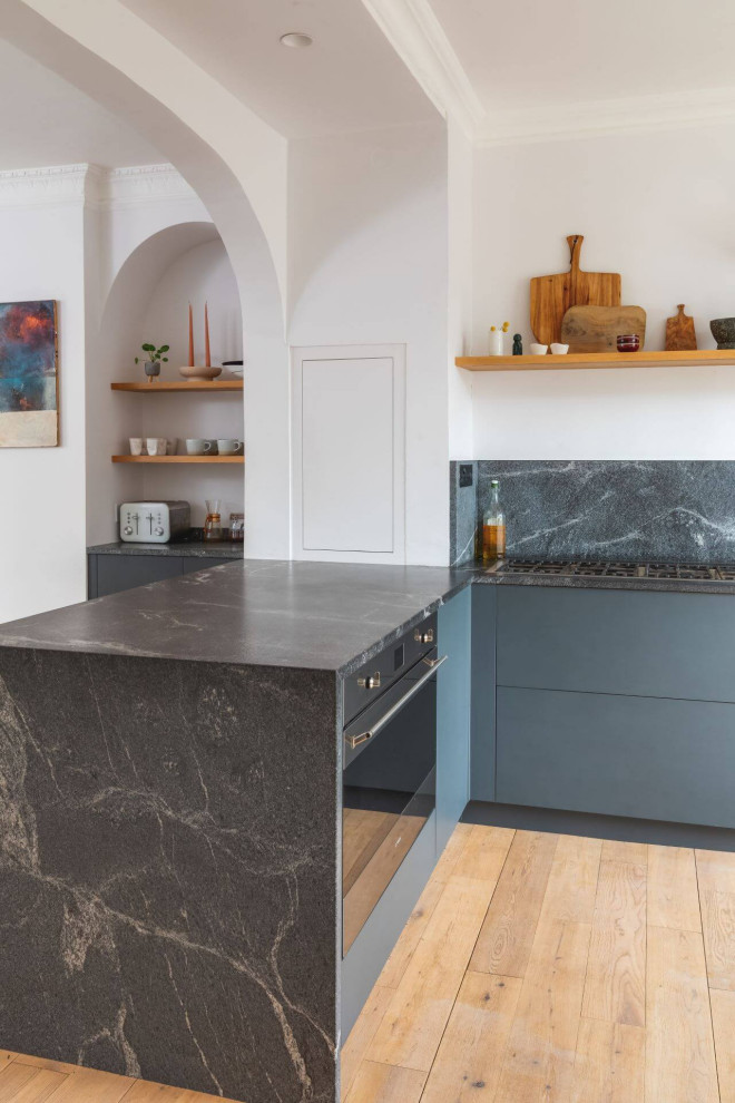 Inspiration for a medium sized modern l-shaped open plan kitchen in Other with a single-bowl sink, flat-panel cabinets, black cabinets, granite worktops, black splashback, granite splashback, black appliances and black worktops.