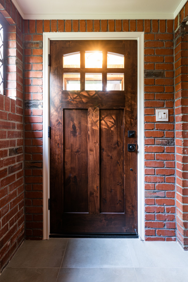 Ispirazione per una porta d'ingresso chic di medie dimensioni con pareti rosse, pavimento con piastrelle in ceramica, una porta singola, una porta in legno scuro, pavimento grigio e pareti in mattoni