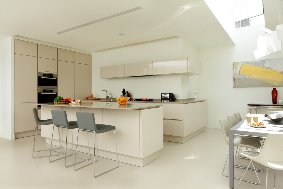 Photo of a large contemporary l-shaped open plan kitchen in London with an integrated sink, flat-panel cabinets, beige cabinets, solid surface benchtops, stainless steel appliances and with island.