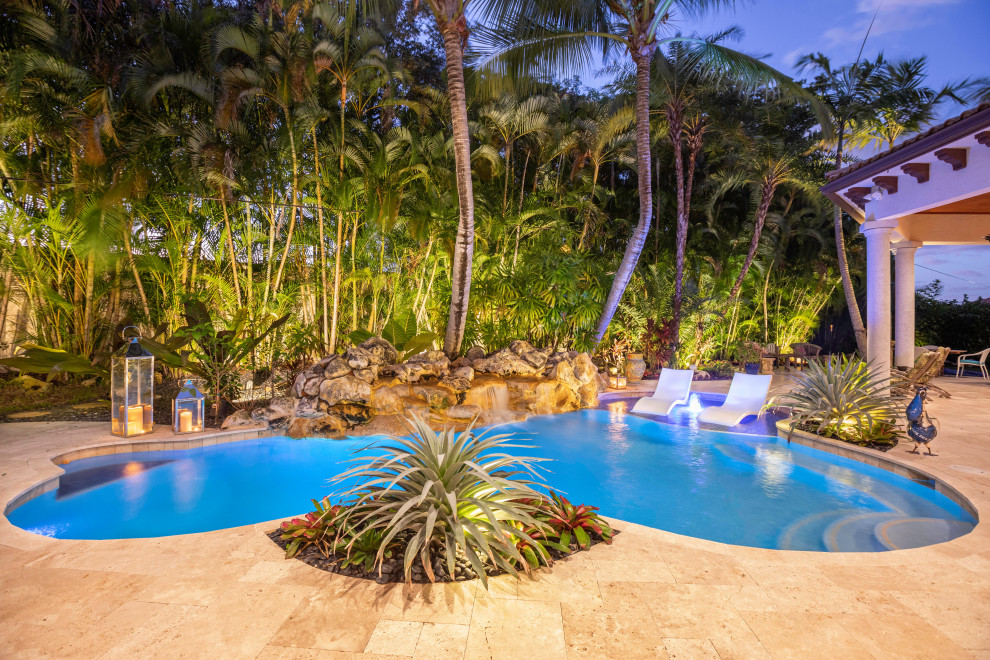 Inspiration for a large tropical backyard custom-shaped lap pool in Miami with tile.