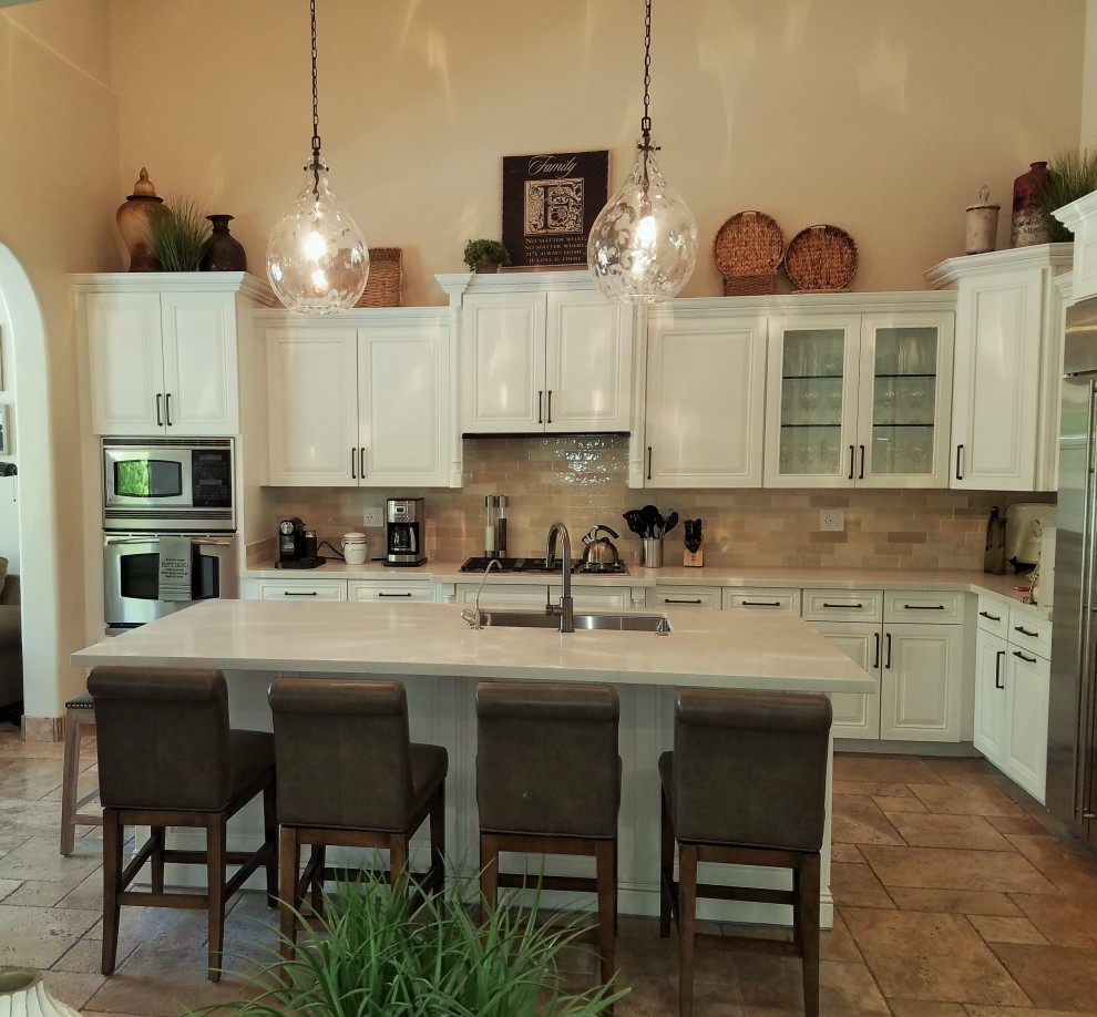 Transitional travertine floor and beige floor kitchen photo in Minneapolis with a single-bowl sink, raised-panel cabinets, white cabinets, quartzite countertops, beige backsplash, ceramic backsplash, stainless steel appliances, an island and white countertops
