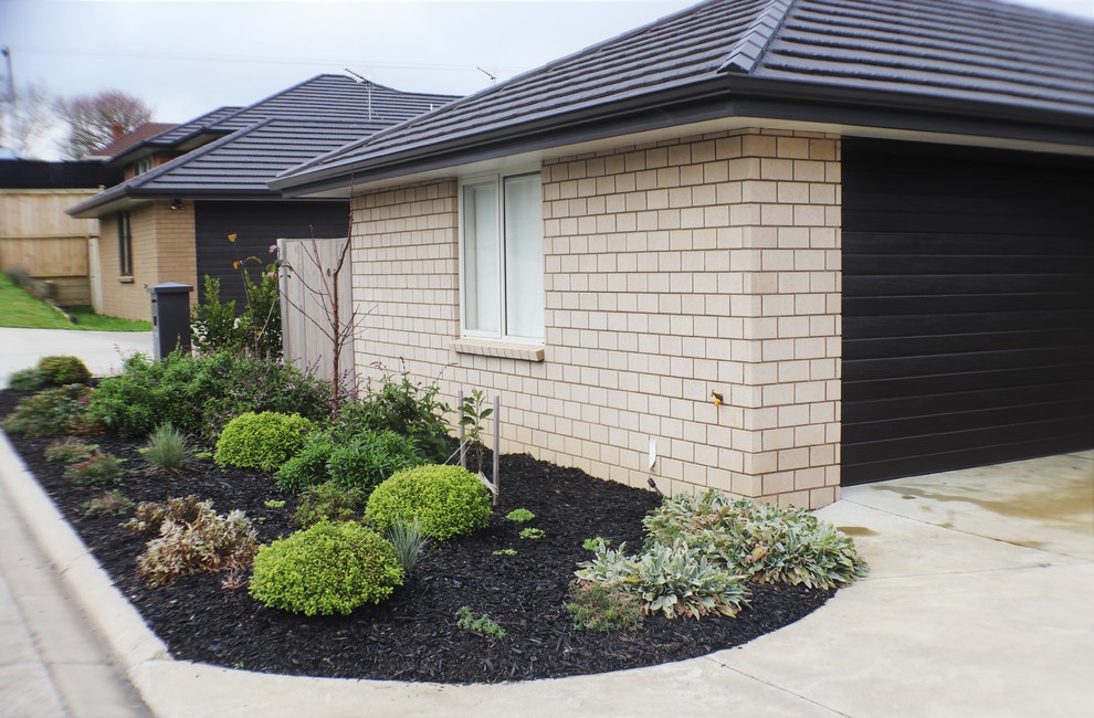 Photo of a mid-sized country front yard partial sun garden for summer in Auckland with brick pavers.