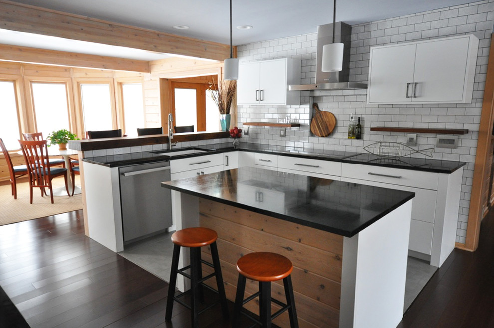 Mid-sized transitional l-shaped dark wood floor eat-in kitchen photo in Grand Rapids with an undermount sink, flat-panel cabinets, white cabinets, soapstone countertops, white backsplash, subway tile backsplash, stainless steel appliances and an island