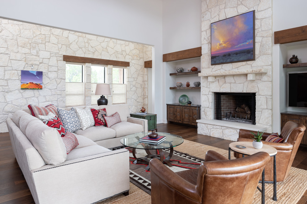 Photo of a mid-sized open concept family room in Austin with a standard fireplace, a stone fireplace surround, brown floor, white walls, dark hardwood floors and a wall-mounted tv.