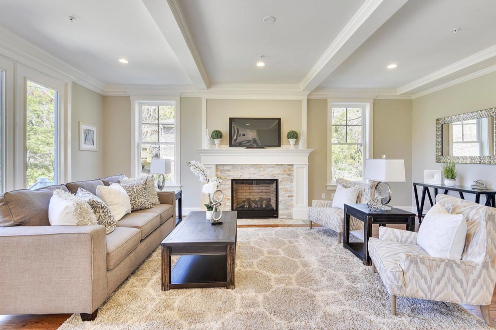 This is an example of a large traditional enclosed living room in DC Metro with medium hardwood floors, a standard fireplace, a stone fireplace surround, a wall-mounted tv, beige walls and brown floor.