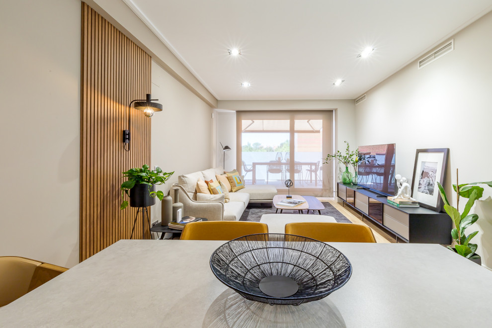 На фото: изолированная, серо-белая гостиная комната среднего размера в современном стиле с серыми стенами, светлым паркетным полом, отдельно стоящим телевизором, коричневым полом и деревянными стенами с
