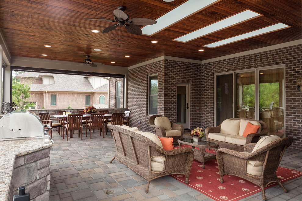 Transitional backyard verandah in Cincinnati with an outdoor kitchen, natural stone pavers and a roof extension.