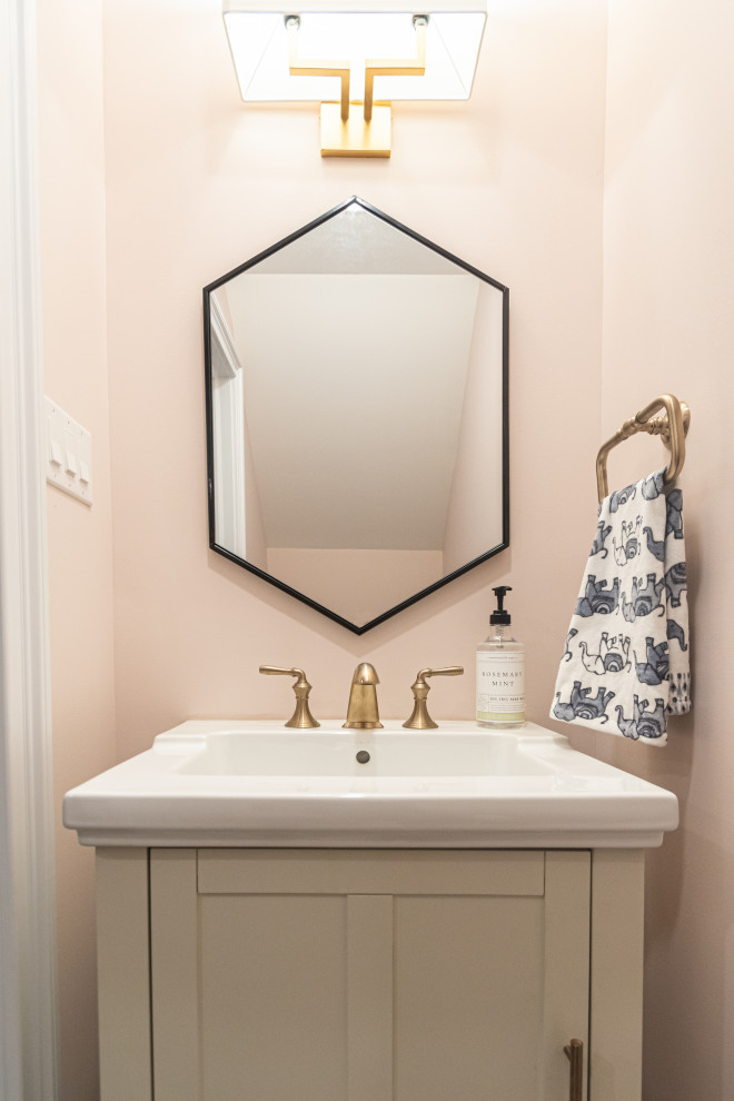 This is an example of a small transitional powder room in Philadelphia with recessed-panel cabinets, beige cabinets, pink walls, porcelain floors, a pedestal sink, grey floor and white benchtops.