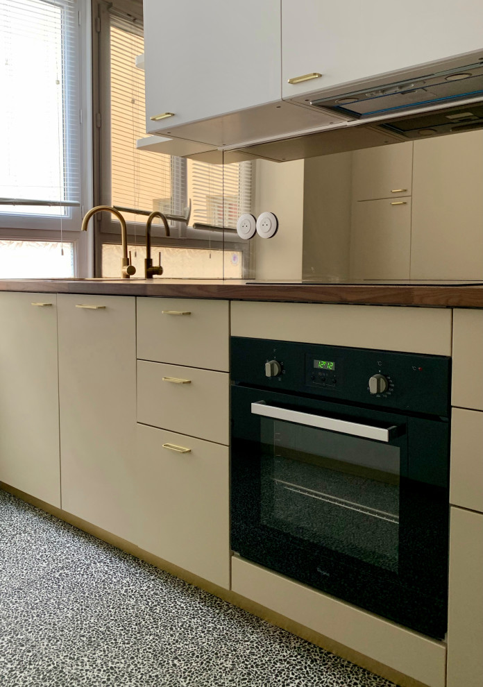 Cette photo montre une cuisine chic avec des portes de placard beiges, un plan de travail en bois, une crédence miroir, un sol en terrazzo et un sol multicolore.