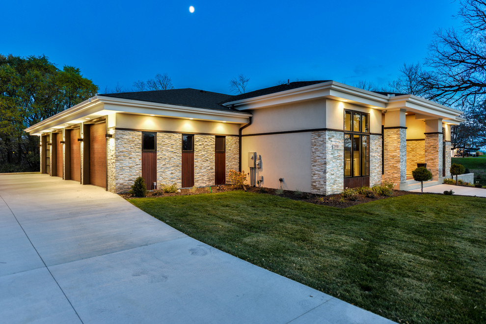 This is an example of a large contemporary one-storey stucco beige exterior in Minneapolis with a hip roof.