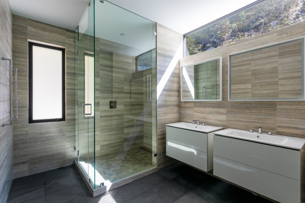 Design ideas for a mid-sized contemporary master bathroom in Vancouver with flat-panel cabinets, white cabinets, a corner shower, beige tile, travertine, slate floors, an integrated sink, black floor, a hinged shower door, white benchtops, a double vanity and a floating vanity.