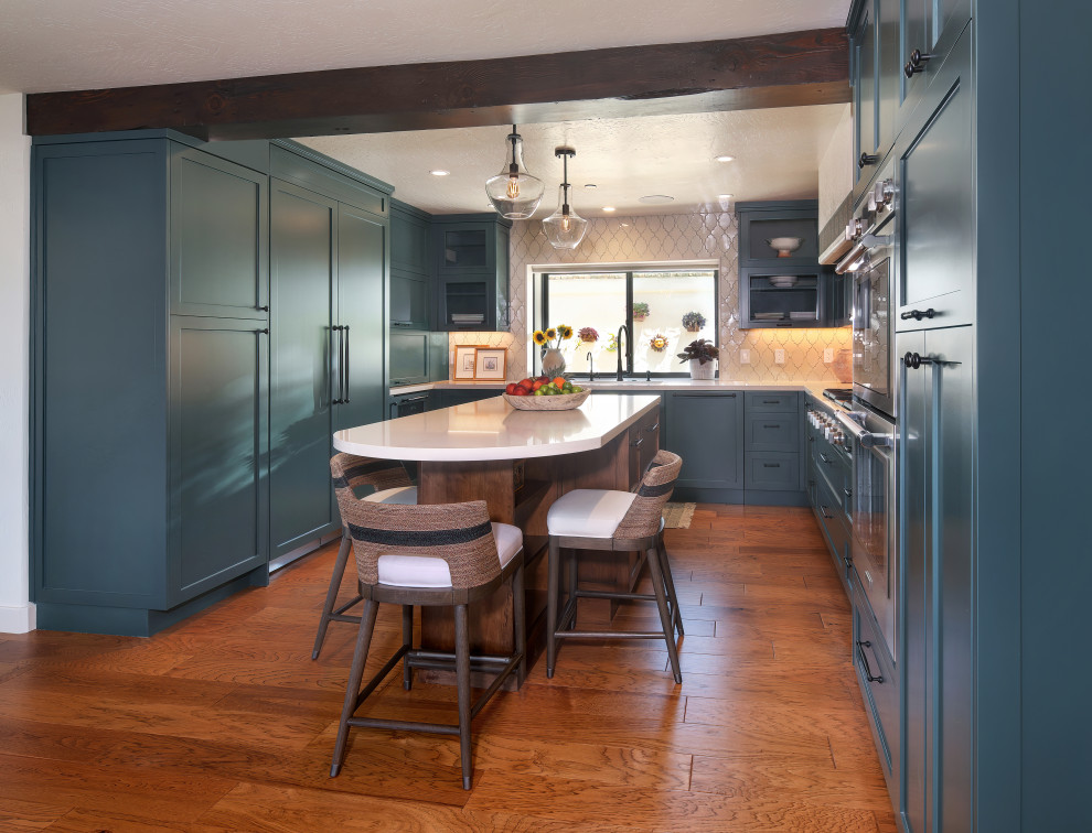 Foto på ett avskilt, stort medelhavsstil beige u-kök, med en undermonterad diskho, skåp i shakerstil, gröna skåp, bänkskiva i kvarts, beige stänkskydd, stänkskydd i keramik, integrerade vitvaror, mellanmörkt trägolv, en köksö och brunt golv