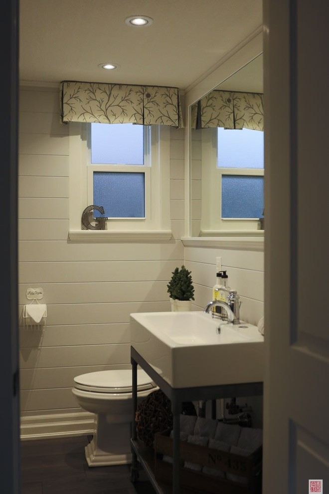 This is an example of a small transitional powder room in Toronto with a two-piece toilet, white tile, medium hardwood floors and an integrated sink.