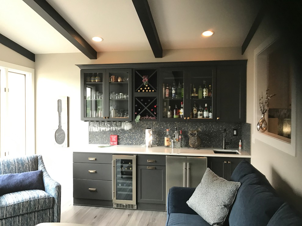 This is an example of a mid-sized contemporary single-wall wet bar in Other with an undermount sink, recessed-panel cabinets, black cabinets, quartz benchtops, blue splashback, metal splashback, vinyl floors and grey floor.