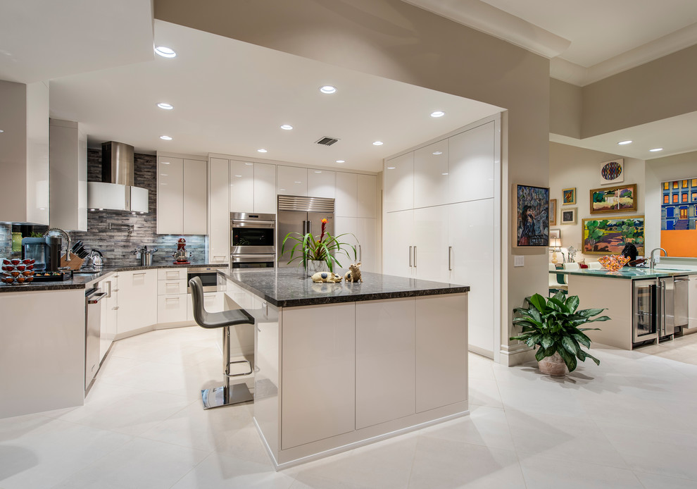 Inspiration for a mediterranean beige floor kitchen remodel in Other with flat-panel cabinets, white cabinets, stainless steel appliances, an island and black countertops